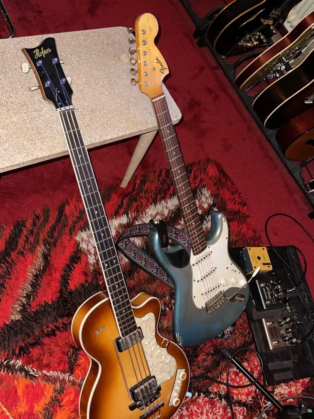 Two guitars on a red rug
